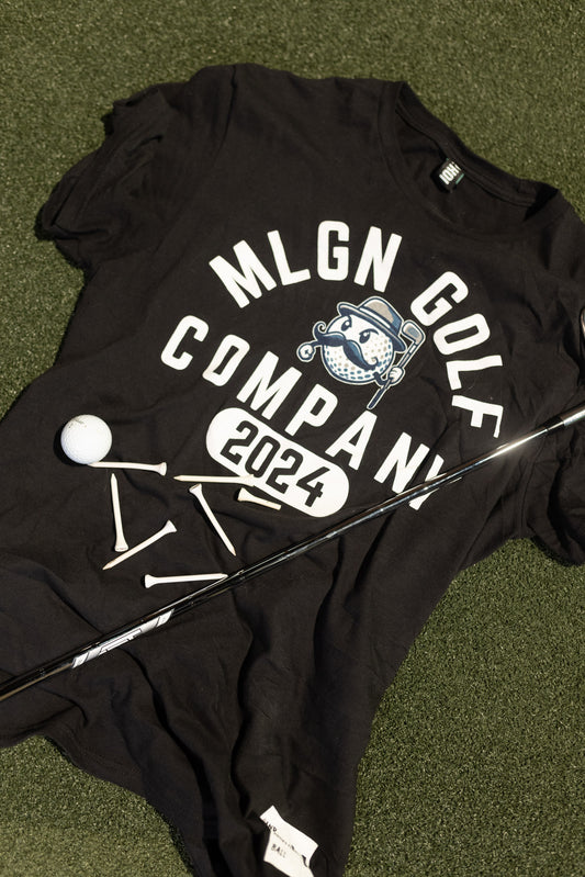 This is the MLGN "Built" black, ringspun, t-shirt with the Mully logo centered on the shirt with the words MLGN GOLF arched over the logo and the word COMPANY and 2024 underneath the logo.
On the bottom right corner of the shirt there is a small white coloured screened on feature tag that reads "Hand Me Another Ball" in black writing. The letters MGC are beside the Hand Me Another Ball saying.